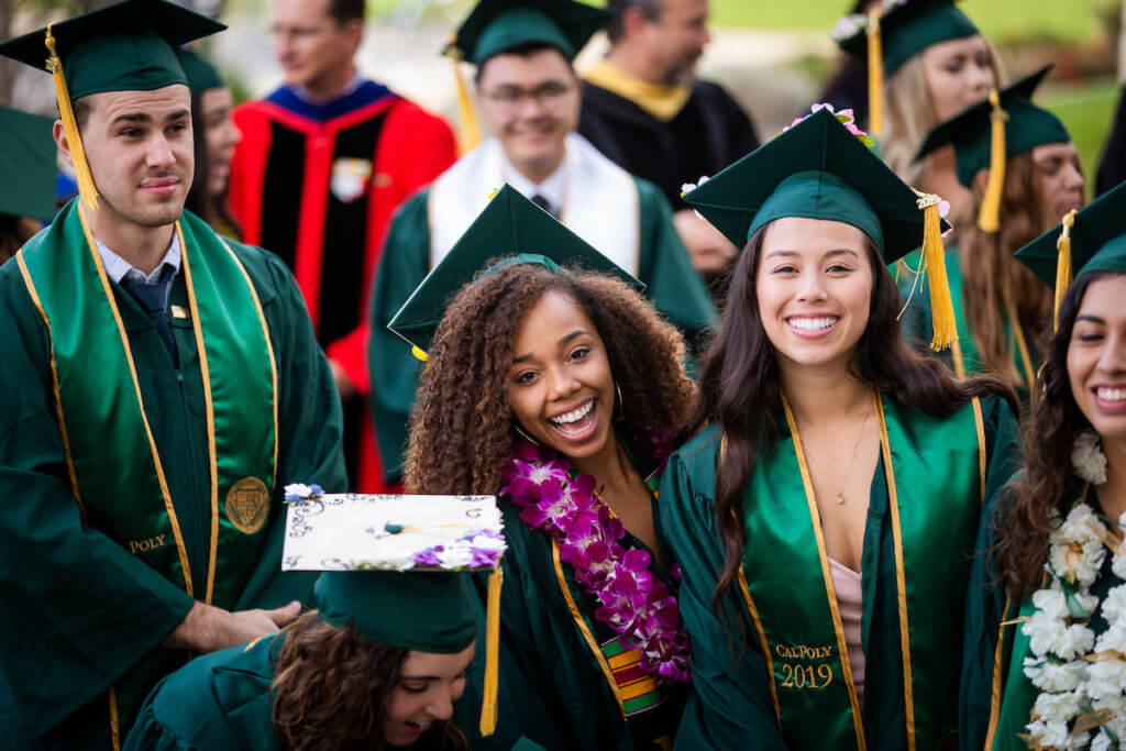 A cropped image of graduating seniors in regalia smiling during the Cal Poly Commencement ceremony